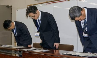 　記者会見で頭を下げる大阪市教育委員会の乗京慎二第３教育ブロック担当部長（中央）ら＝２０日午後、市役所