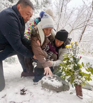 　父親の神庭利太さんが眠る墓石に手を触れるロサリナ・カンバ・フェルナンデスさん（中央）＝３０日午前、鳥取県伯耆町