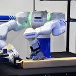 　人の両腕の動きを模倣し梱包作業をする安川電機のロボット＝２０２５年１２月、東京都江東区