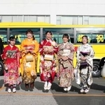 　「はとバス二十歳を祝う会」で、記念写真に納まる２０歳になるガイドの女性と整備士の男性＝６日午前、東京都大田区