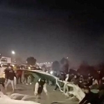 　イラン北東部ホラサンラザビ州で、イラン国旗を引き裂く人々＝８日公開（ソーシャルメディアから・ロイター＝共同）