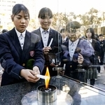 　「１・１７希望の灯り」の分灯が始まり、ろうそくに火を移す中学生＝１０日午後、神戸市中央区の東遊園地