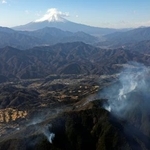 　延焼が続く山梨県上野原市の扇山（手前）。奥は富士山＝１１日午前１０時２５分（共同通信社ヘリから）