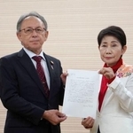 　山内末子県議（右）から沖縄県知事選への出馬要請書を受け取る玉城デニー知事＝１３日午後、那覇市
