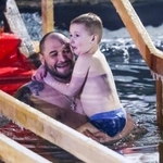 　ロシア正教の「主の洗礼祭」に合わせ、子どもを抱いて沐浴する男性＝１８日、モスクワ（タス＝共同）