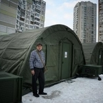 　２５日、ウクライナ・キーウに設けられた緊急暖房設備の前に立つ地元住民（ゲッティ＝共同）