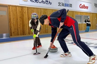 　授業で小学生（左）にカーリングを教える常呂高の生徒＝１月、北海道北見市のアドヴィックス常呂カーリングホール（常呂高提供）