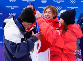 　スノーボード女子スロープスタイルで優勝した深田茉莉（右）から金メダルをかけてもらう佐藤康弘コーチ。中央は練習仲間で五輪王者の蘇翊鳴＝１８日、イタリア・リビーニョ（共同）