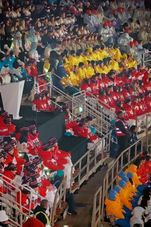 　閉会式を観客席から見つめる、水色と白のダウン姿のＡＩＮの選手ら（左上）。右下は水色の帽子と黄色のダウンを身につけたウクライナの選手ら＝２２日、イタリア・ベローナ（共同）