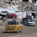 　イスラエルの攻撃で破壊された住宅のがれきの間を通るパレスチナの人々の車＝４日、ガザ市（ロイター＝共同）