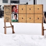 　周囲が雪で覆われた、秋田県男鹿市内の衆院選候補者のポスター掲示板＝４日