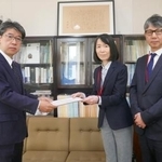 　文科省の望月禎初等中等教育局長（左）に、意見書を手渡す日本新聞協会の坂口佳代ＮＩＥ委員会委員長（中央）＝６日、東京都千代田区（日本新聞協会提供）