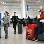 　春節に伴う大型連休に入り、スーツケースを引いて北京首都国際空港内を移動する人たち＝１５日（共同）