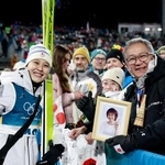 　女子個人ラージヒルを終え、母信子さんの写真を持つ父守さん（右）と撮影に応じる丸山希＝プレダッツォ（共同）