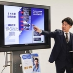 　ＳＮＳ型投資詐欺について説明する警察官＝１８日午前、愛知県警本部