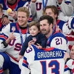 　ジョニー・グドローの背番号１３のユニホームを掲げ、グドローの幼い子供を抱いて記念撮影に納まるディラン・ラーキンら米国の選手たち＝２２日、ミラノ（ＡＰ＝共同）