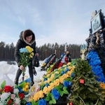 　ロシアのウクライナ侵攻開始から４年となった２４日、首都キーウ近郊イルピンにある墓地で、戦没した息子の墓に献花する女性（共同）