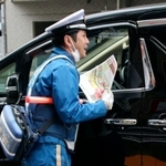 　路線バスの発進を妨げる危険性についてのチラシを配る警視庁の警察官＝２６日午前、東京都大田区