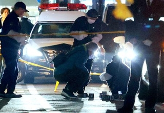 　女性が刺されたと通報があった現場付近の路上を調べる捜査員＝６日午後７時４４分、富山市