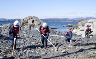 　宮城県南三陸町の沿岸部で、行方不明者の手がかりを求め捜索する警察官＝２０２４年３月
