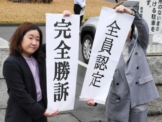 　判決後、垂れ幕を掲げる原告側の弁護士＝１２日午後、新潟市