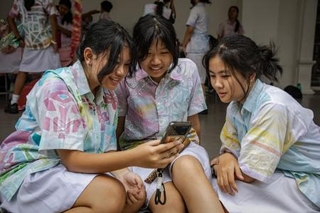 　友人とスマートフォンでＴｉｋＴｏｋを見る１４歳の少女（左）＝２７日、インドネシア・ジョクジャカルタ（ゲッティ＝共同）