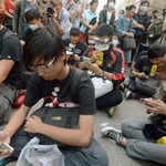 　香港・九竜地区モンコックで、幹線道に座り込み、スマートフォンをいじるデモ隊＝２０１４年