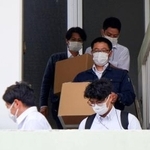 　辺野古沖の転覆事故で死亡した船長の関係先から段ボール箱を運び出す海保の職員ら＝２５日午後、沖縄県南城市