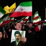 　イラン新最高指導者モジタバ・ハメネイ師の写真を持つ支持者ら＝２５日、テヘラン（ＡＰ＝共同）