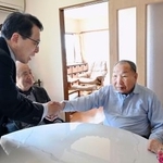 　袴田巌さんと握手を交わす村山浩昭元裁判官（左）＝２７日午後、浜松市