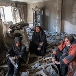 　イランの首都テヘランで、攻撃で壊れた住宅のがれきの上に座り込む住民たち＝３０日（ゲッティ＝共同）