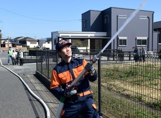 　防災訓練で放水する冨玖チュアンさん＝３月、熊本県合志市