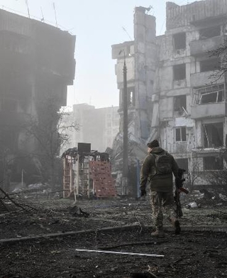 　ロシア軍の攻撃を受けた住宅近くを歩くウクライナ兵＝３月、ウクライナ南部ザポリージャ州オリヒウ（ロイター＝共同）