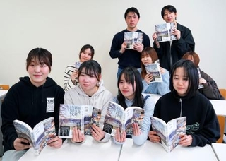 　出版された「福島、語り継ぐ生活史」を手にする、福島第１原発事故の被災地を回り、住民らにインタビューを行った福島大の学生たち＝３月、福島市
