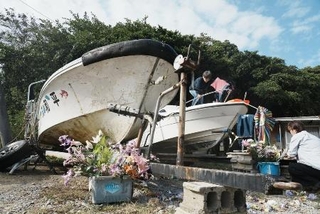 　辺野古沖で転覆した船「平和丸」（左）と「不屈」に花を供える人たち＝３月、沖縄県名護市