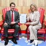 　大阪・関西万博のカナダ館に展示されていた「赤い椅子」に座る関西エアポートのブノア・リュロ副社長（左）＝１３日午前、関西空港