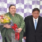 　引退記者会見を終え花束を手にする元幕内剣翔。右は追手風親方＝１４日、東京・両国国技館