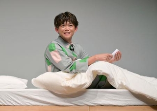 　パジャマ姿で寝付き対策を実践する松丸亮吾＝東京都中央区
