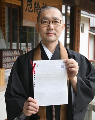 　点字おみくじを持つ根本聖道さん＝東京都中野区