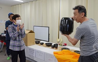 　能登の瓦を材料とした信楽焼の花瓶を手にする小川公男さん。左は大倉好子さん＝４日、石川県輪島市門前町