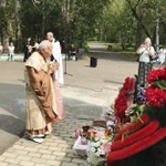 　ロシア極東アムール州のイワノフカにある「哀悼の碑」の前で、手を合わせる横山周導さん（中央）＝２０１８年８月（共同）