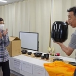 　能登の瓦を材料とした信楽焼の花瓶を手にする小川公男さん。左は大倉好子さん＝４日、石川県輪島市門前町