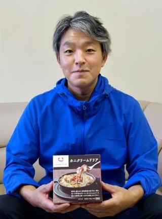 　カニクリームドリアを手にする前田水産の前田哲弥社長＝２０２４年１０月、鳥取県米子市