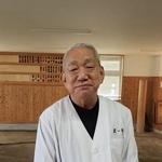 　自らの木札が掛かった稽古場の前に立つ柿川信登さん＝２０２４年１１月、福岡市東区の佐渡ケ嶽部屋宿舎
