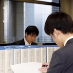 　２０２３年分の政治資金収支報告書（総務相所管の中央分）とチェックする職員＝総務省