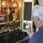 　中坪キミ子さんの遺影が飾られた仏壇に手を合わせる息子の勇成さん＝１１月、富山市