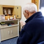 　地震で犠牲になった妻と長男の骨つぼが置かれた仏壇に、手を合わせる出口弥祐さん＝１１月、石川県輪島市
