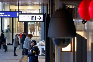 　ＪＲ長野駅前に設置された献花台に手を合わせる人たち（左奥）。近くの交番には防犯カメラが設置されていた＝２６日午後