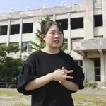 　震災遺構・門脇小前で、被災経験を話す高橋輝良々さん＝２０２４年９月、宮城県石巻市
