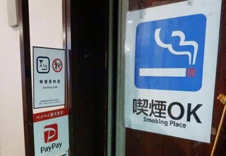　喫煙可能な居酒屋の入り口に張られた「喫煙ＯＫ」と書かれた紙＝２月、東京都千代田区